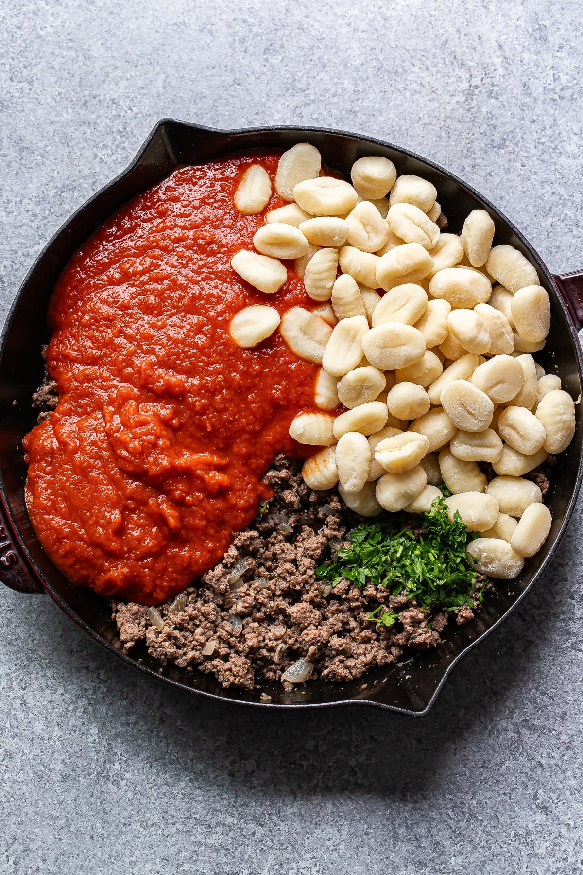 Ground beef, gnocchi, marinara sauce, and parsley in a skillet.
