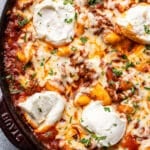 Baked Italian ground beef and gnocchi topped with melted cheese and ricotta in a skillet.