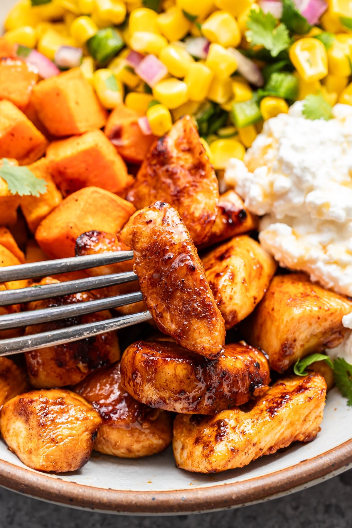 Fork holding a piece of hot honey chicken.
