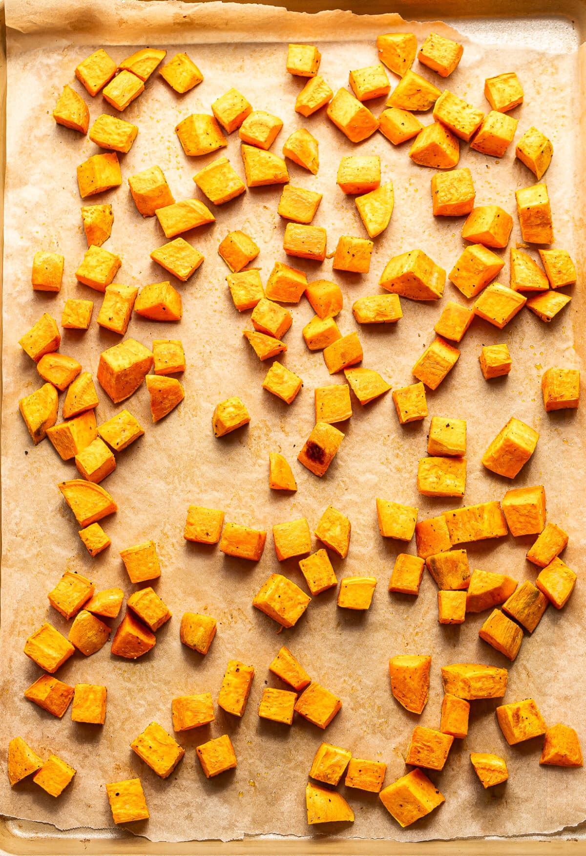 Roasted sweet potato chunks on a sheet pan.