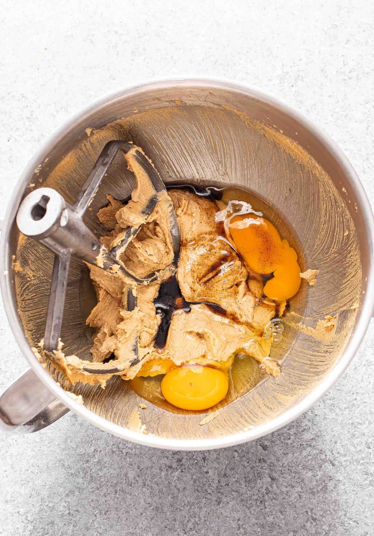 Butter, peanut butter and sugar mixture with eggs and vanilla in a mixing bowl.