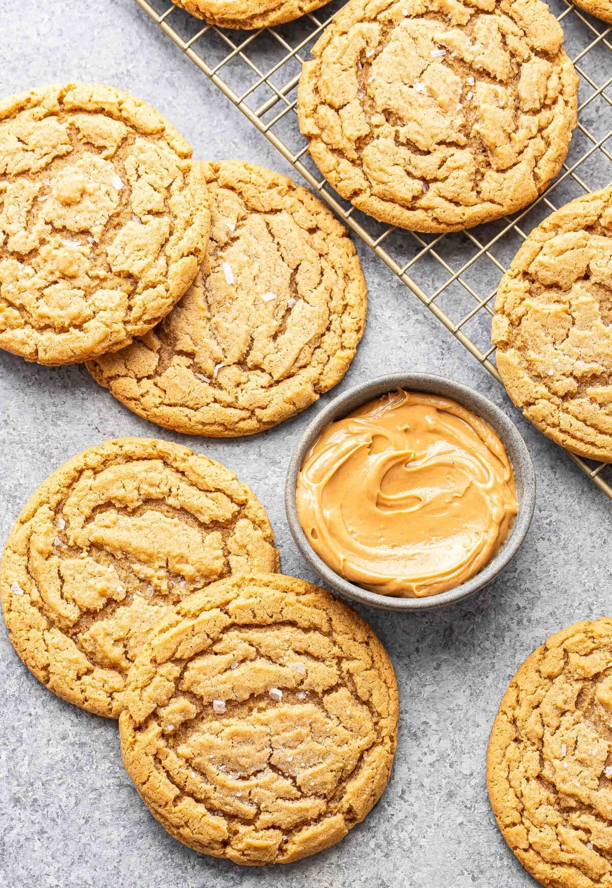 Peanut butter cookies laying next to a small gray bowl with peanut butter in it.