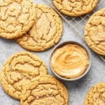 Peanut butter cookies laying next to a small gray bowl with peanut butter in it.