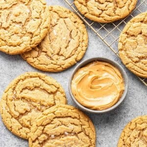 Peanut butter cookies laying next to a small gray bowl with peanut butter in it.