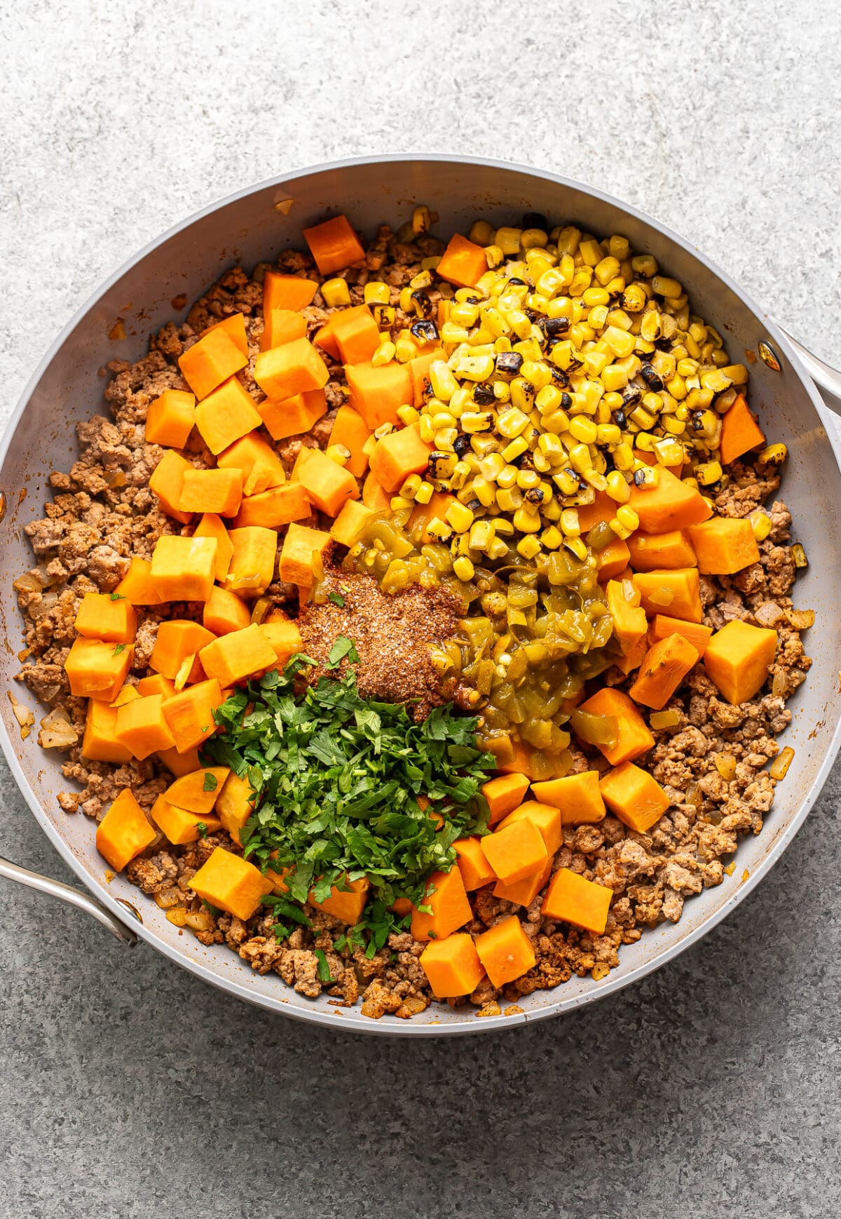 Ground turkey, diced sweet potatoes, corn, green chiles, and cilantro in a skillet.