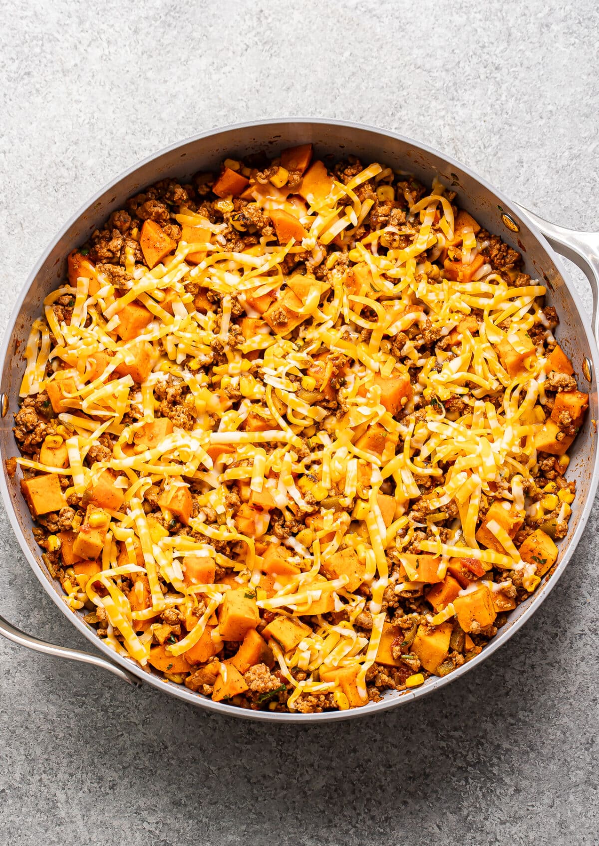 Ground turkey sweet potato skillet with shredded cheese on top.