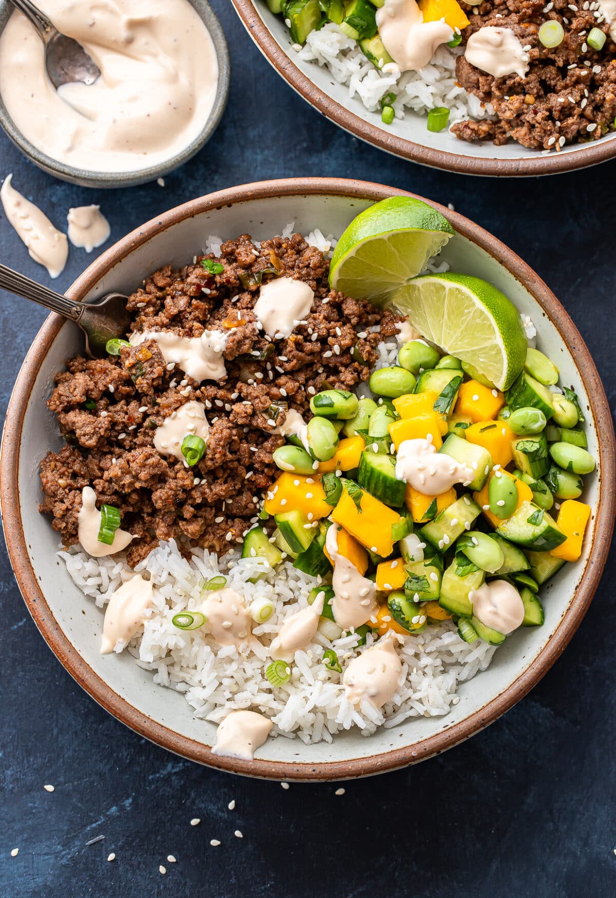 Asian beef bowl with cucumber mango salsa and rice in a white bowl with a fork.