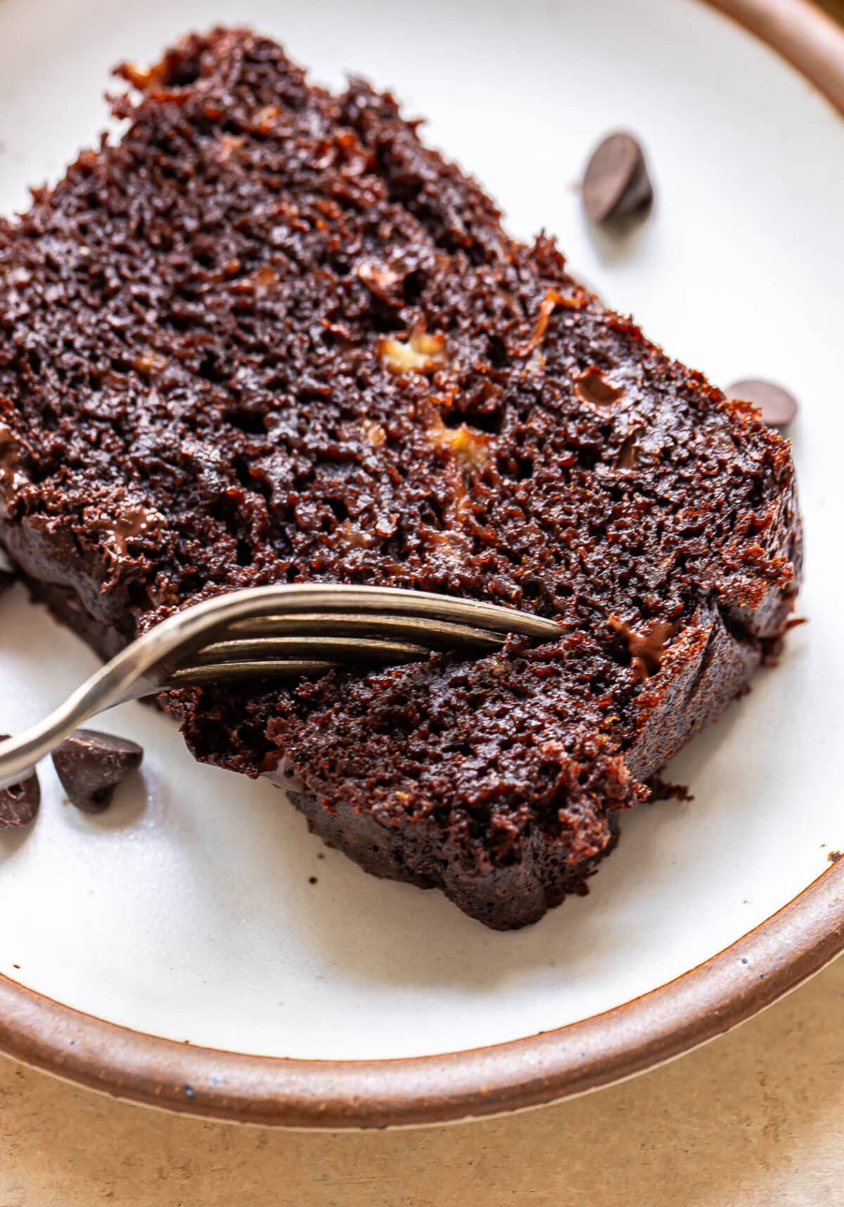 Fork cutting into a slice of chocolate chip banana bread.