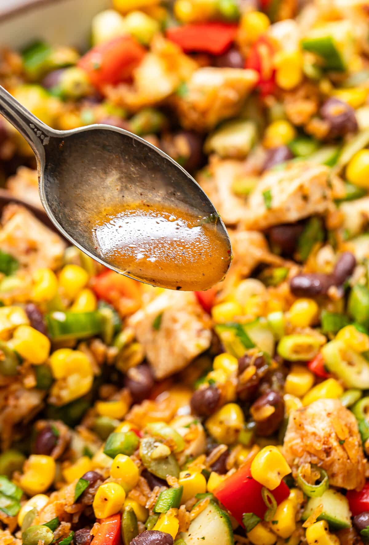Spoon drizzling honey lime vinaigrette onto the southwest crispy rice salad.