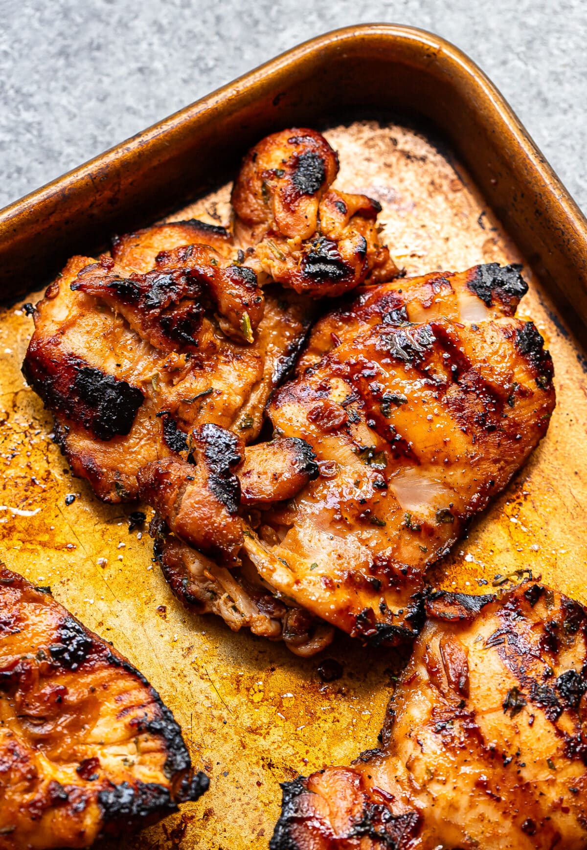 Three pieces of Honey Chipotle Chicken with charred grill marks rest on a golden-brown baking sheet. The chicken appears juicy and well-seasoned, with a slightly caramelized surface that hints at its sweet and smoky glaze.