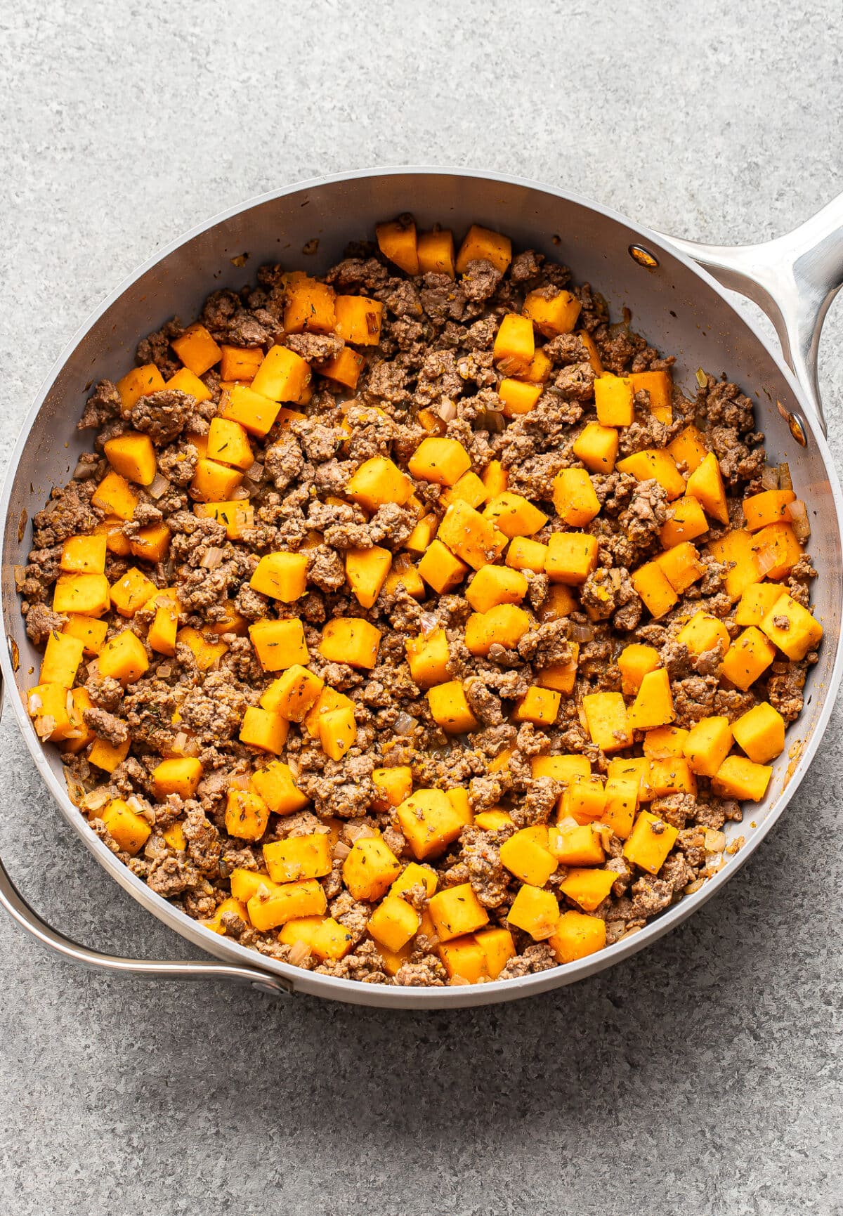 A large pan containing a mixture of cooked ground beef and cubed butternut squash.