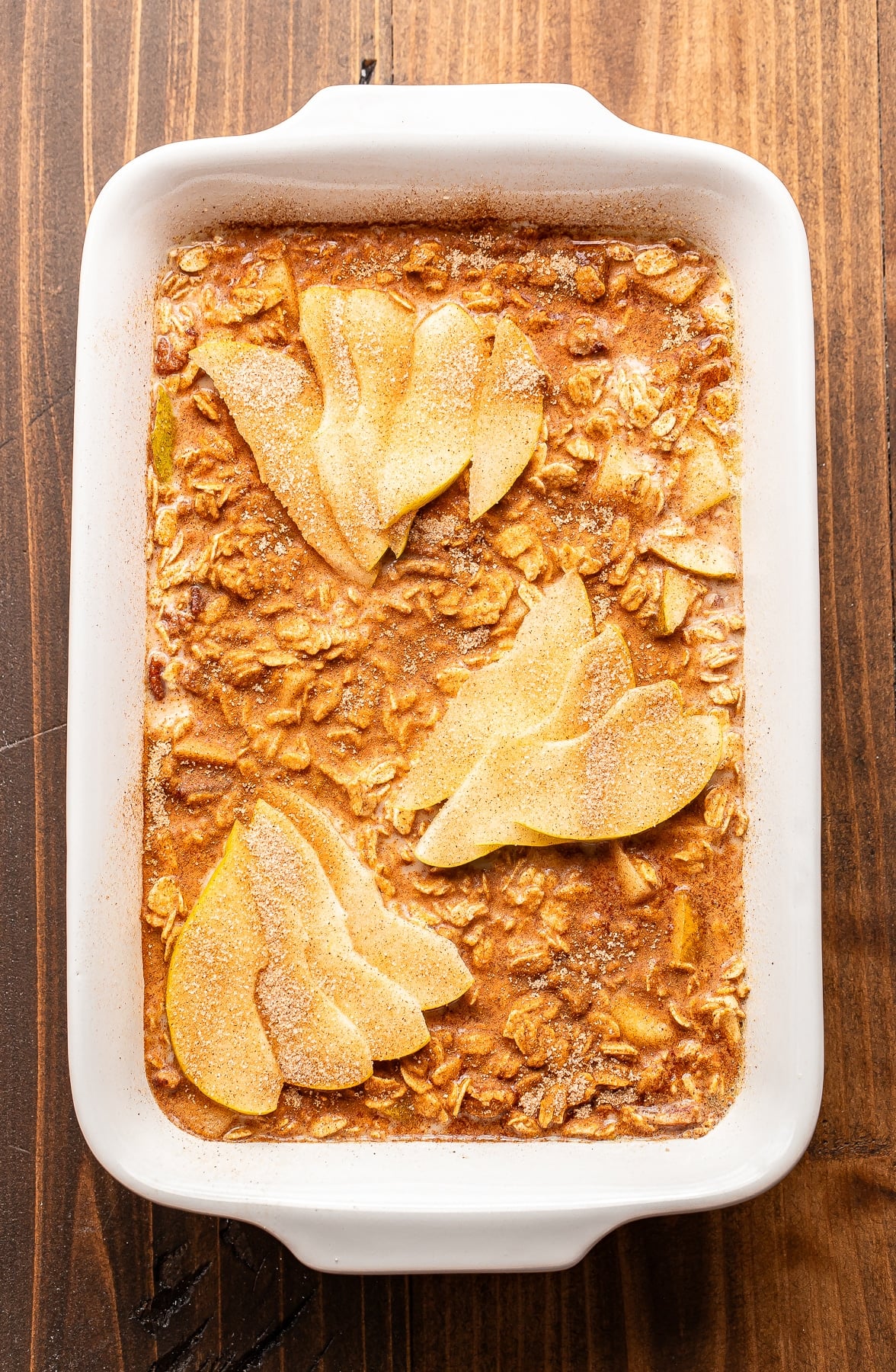 Pear baked oatmeal in a white baking dish topped with sliced pears and a dusting of cinnamon.